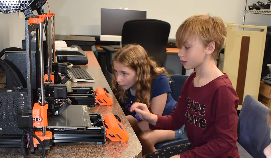 Kids in front of 3D printing machines