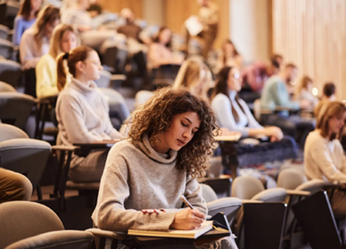 Woman taking notes on a classroom full of students